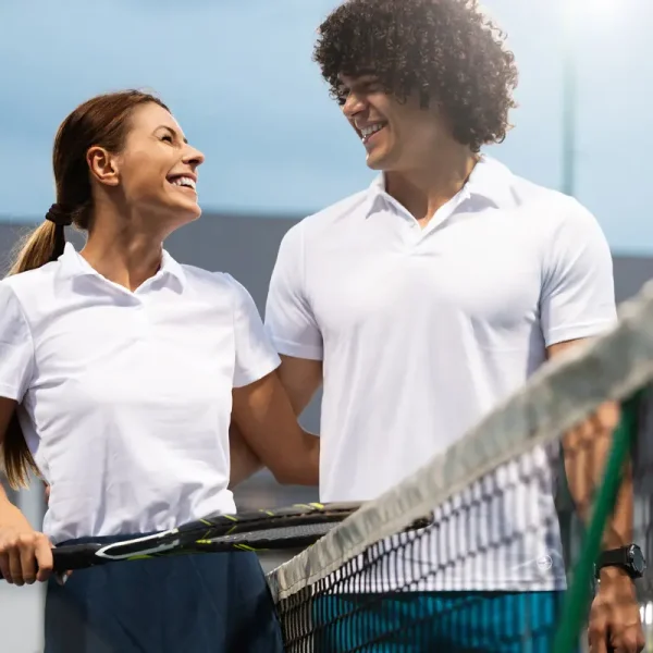 couple en polos blancs jouant au tennis